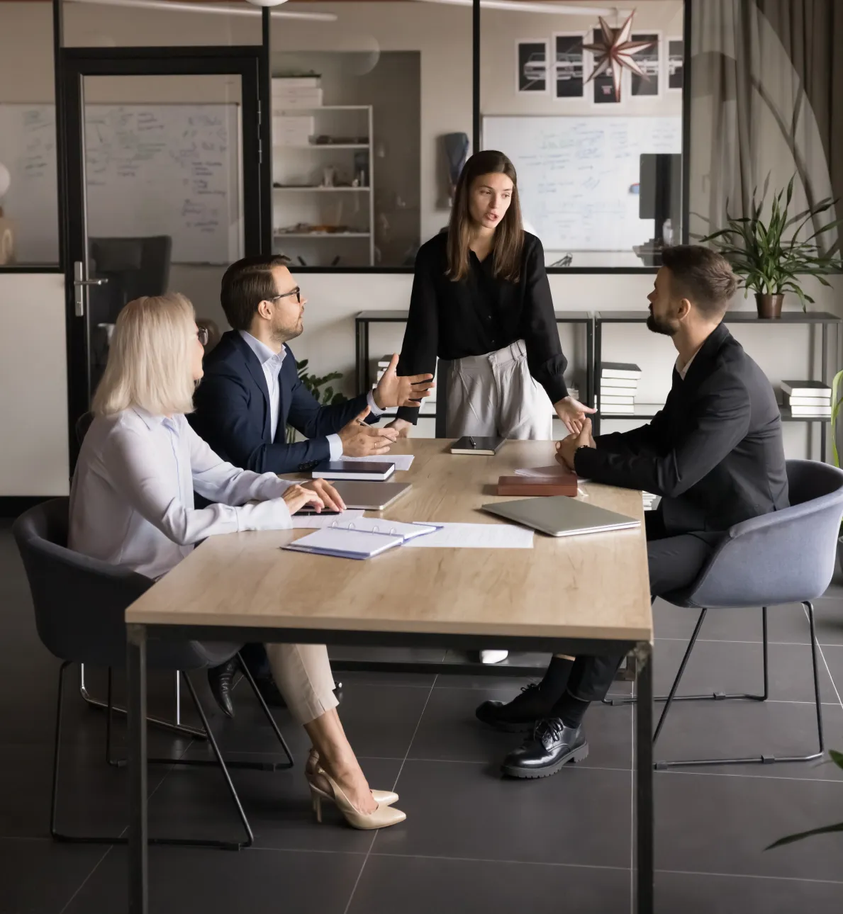 Businesswoman presenting ideas to colleagues seated around table