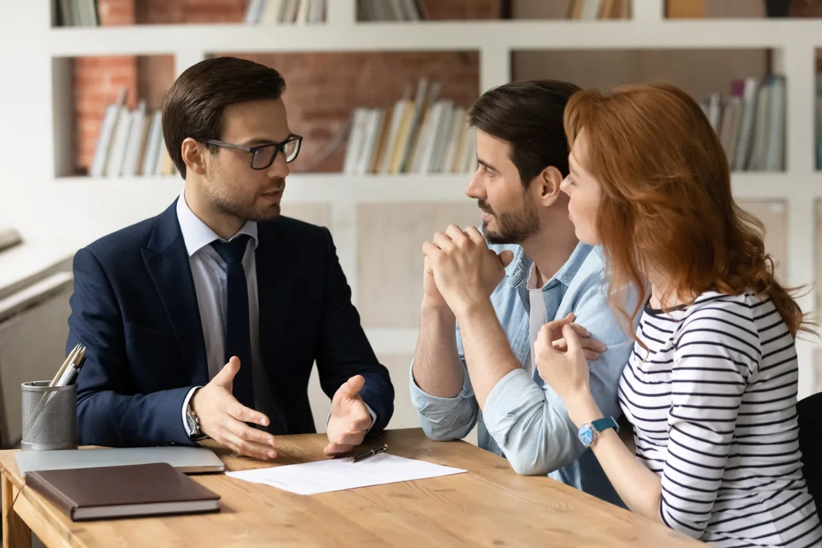 Professional giving financial advice to clients seated around table
