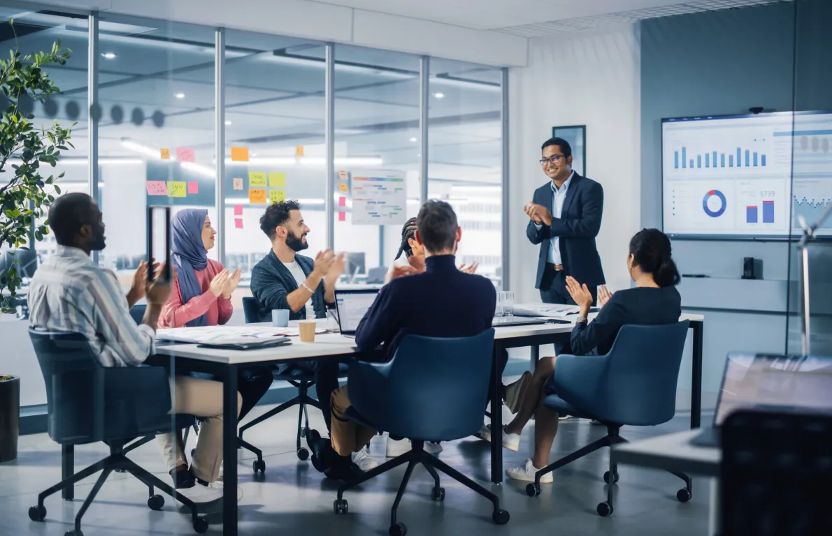 Professional team applauding and smiling around a long conference table